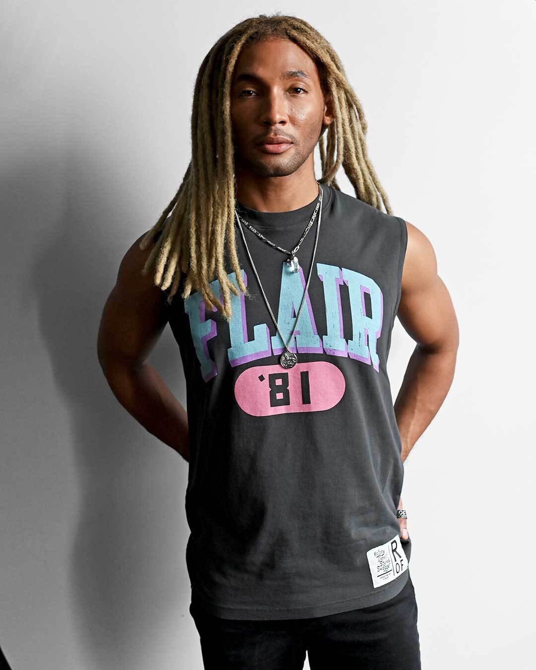 Person wearing sleeveless 'Flair '81' shirt stands against a plain background.